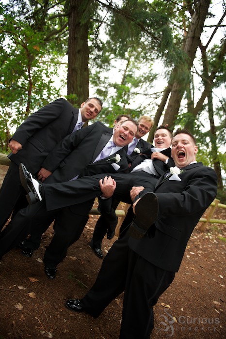 crazy groomsmen hold up groom. yelling and laughing, high energy wedding portrait