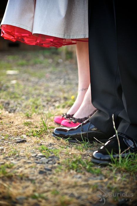 Detail of bride and groom's shoes. Pink heels and shiny black dress shoes.